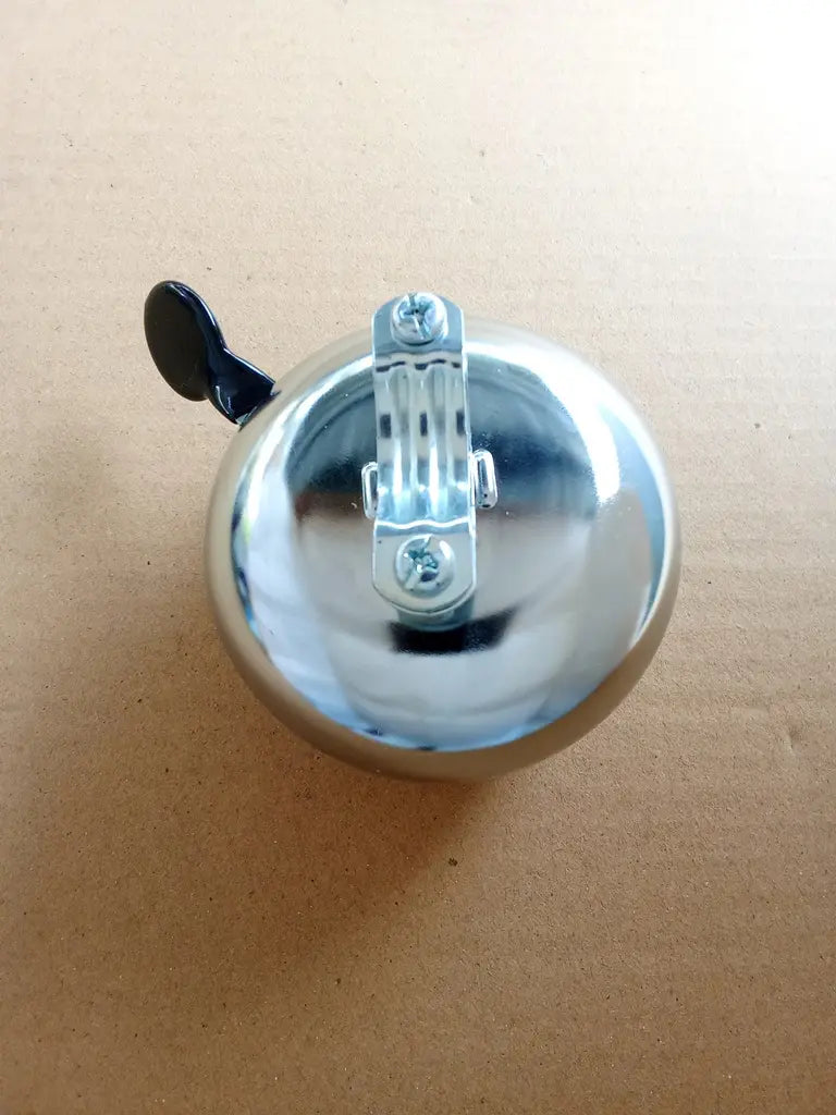 Chrome bicycle bell BSA logo on a beige background back side view