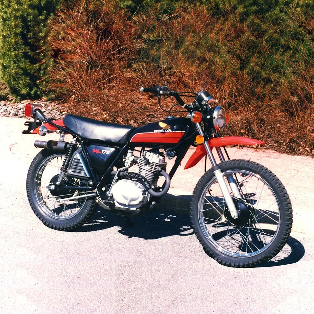 Black and red Honda XL 17 S 1978 motorcycle parked on a paved road with bushes in the background