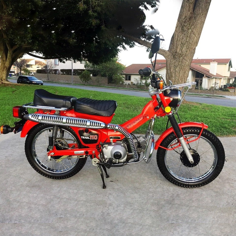 Red motorcycle Honda CT 110 1981 parked on a driveway with a suburban background