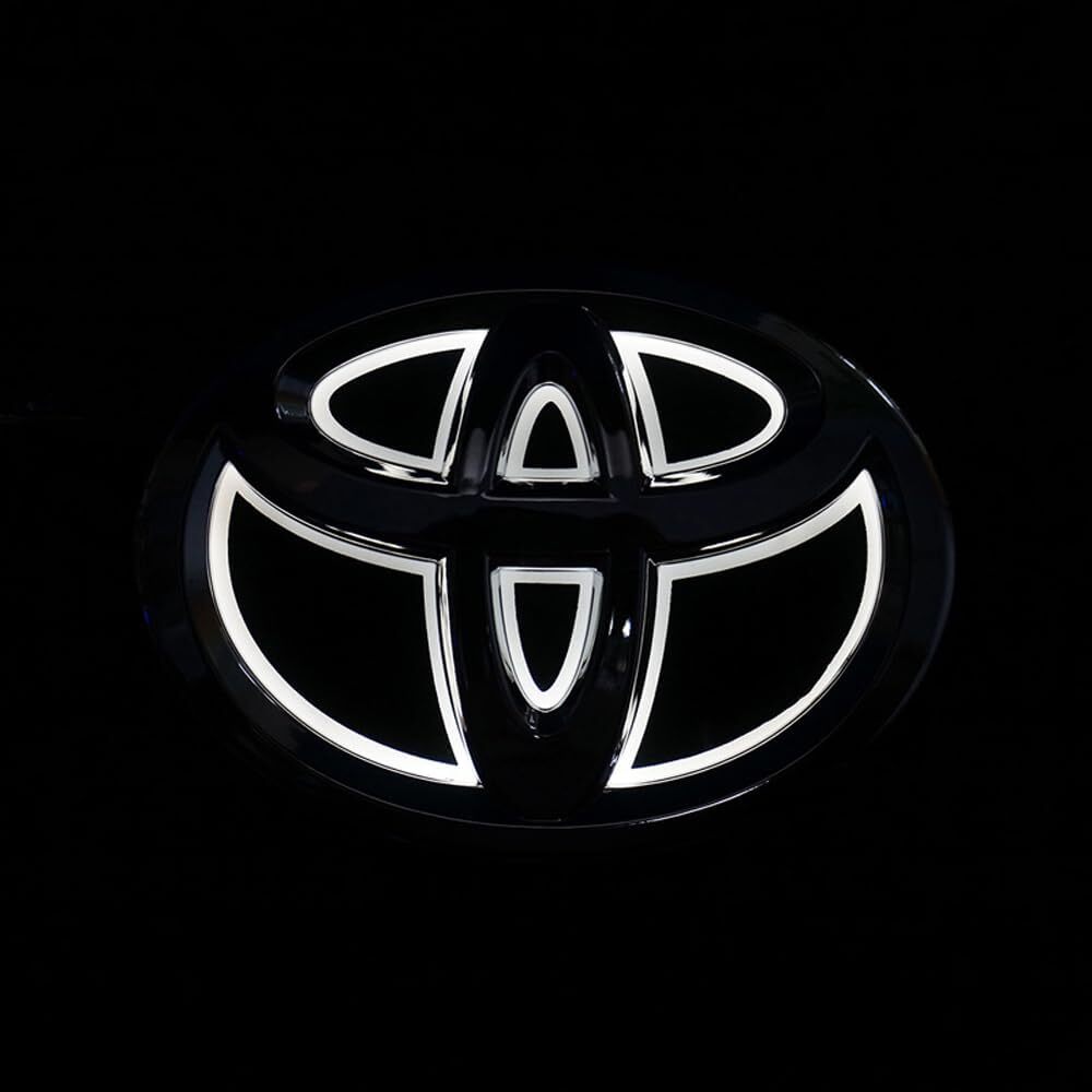 White LED illuminated Toyota front grille emblem glowing brightly at night