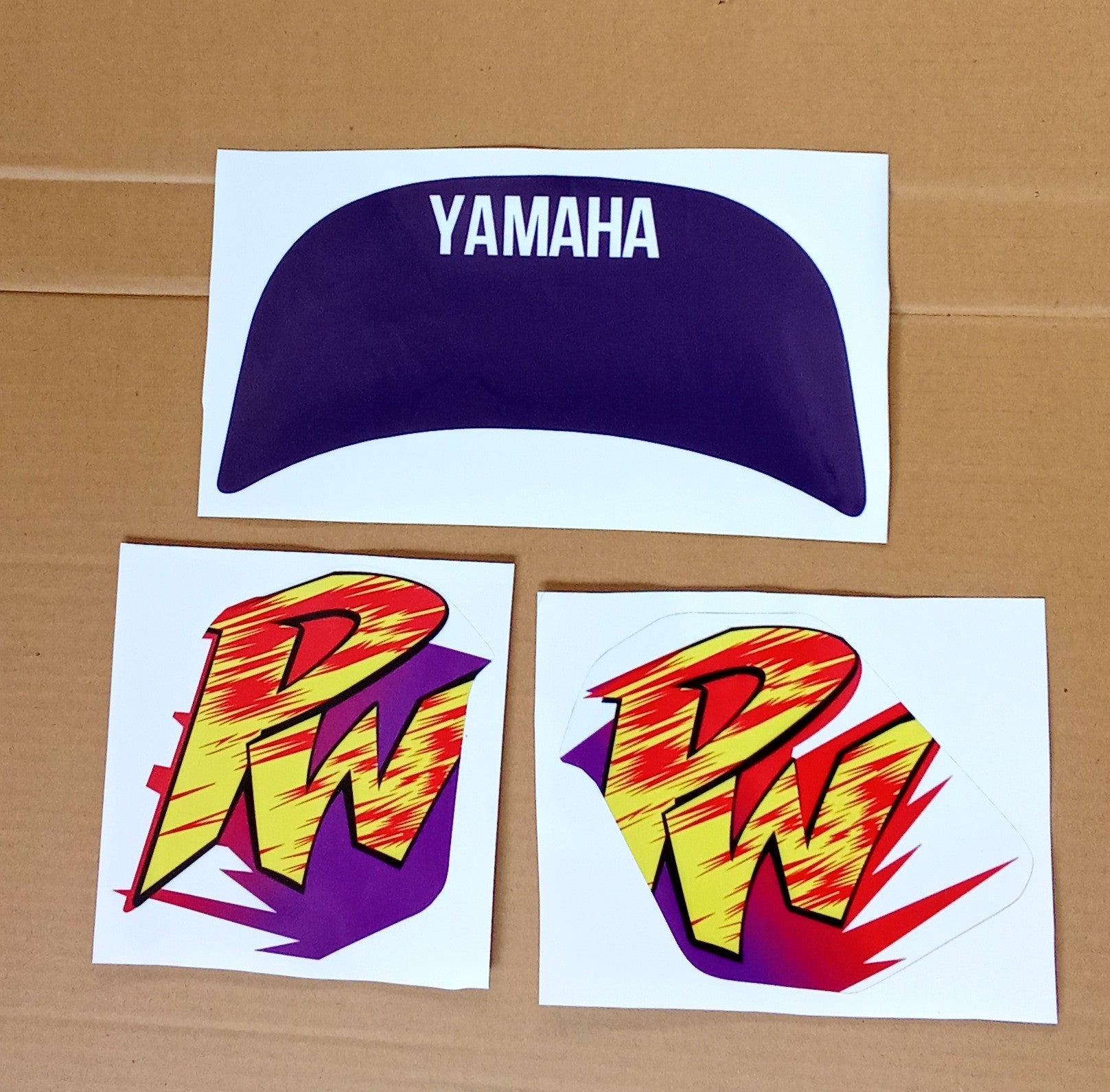 Yamaha logo and colorful 'PW' decals on a cardboard background