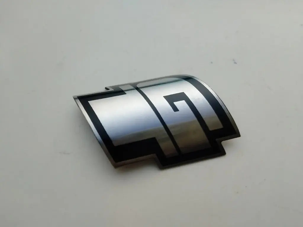 Side profile perspective showing the slim etched stainless steel construction of the GT emblem.