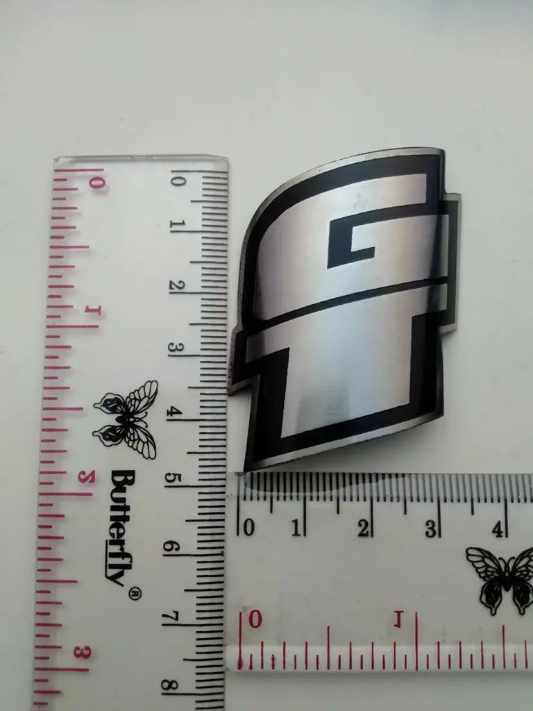 Measurement guide showing height and width dimensions of the handmade GT stainless emblem.