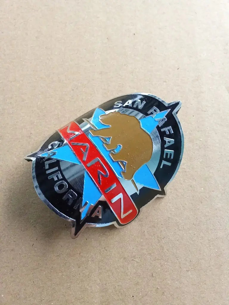 Side profile perspective showing the slim etched stainless steel construction of the Marin San Rafael emblem.