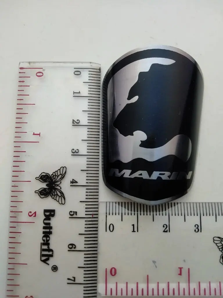 Measurement guide showing height and width dimensions of the handmade Marin stainless emblem.