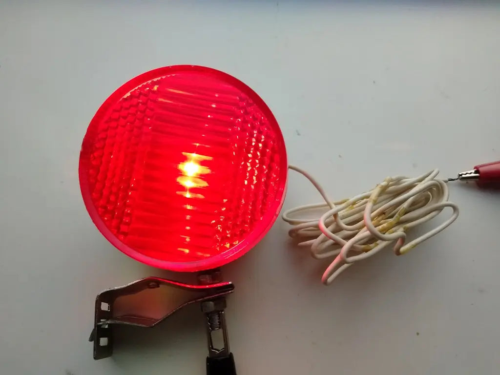 NOS vintage bicycle safety light with metal body, 5.5cm reflector, and metal frame clamp.