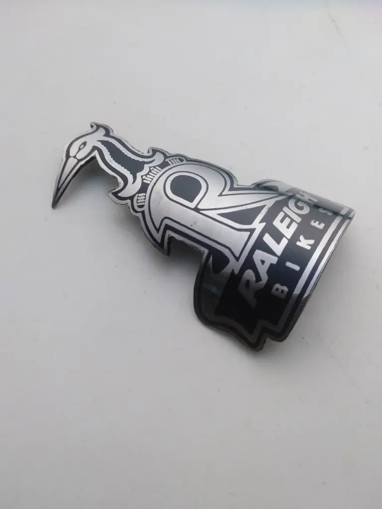 Close-up view of the detailed silver and black enamel Heron logo on the Raleigh steel head badge