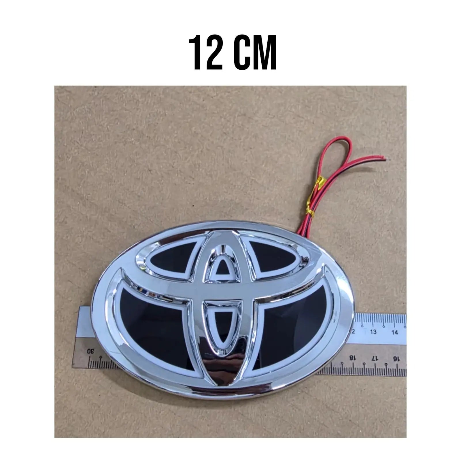 Detailed view of the 2-wire 12V positive and negative electrical leads on the Toyota blue LED badge.
